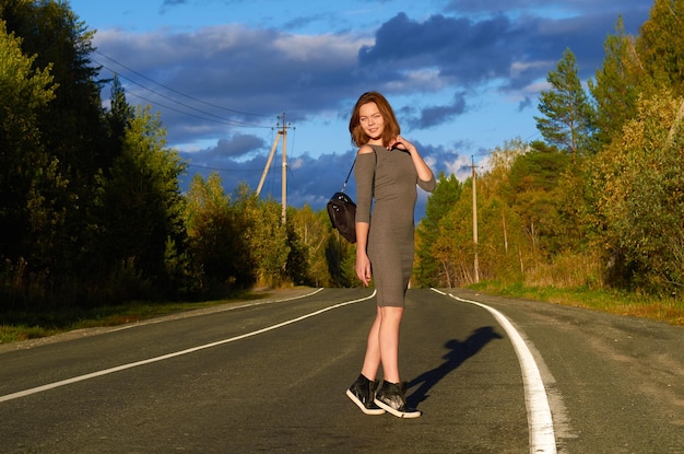 A woman in a gray dress is walking along the road