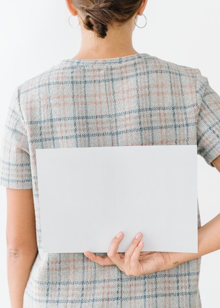 Photo woman in a gray plaid dress showing a blank card on her back