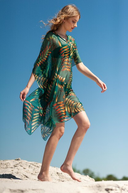 A woman in a green dress walks on a rock.