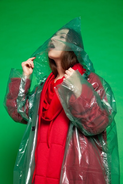 Woman in green raincoat in studio on green background