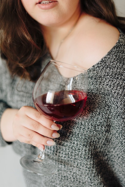 Woman in a grey sweater with a glass of red wine