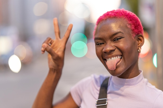 Woman grimacing at camera gesturing victory in a city street