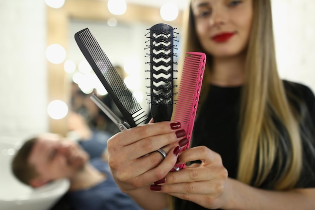 Woman hairdresser holding set of combs and scissors in a barbershop