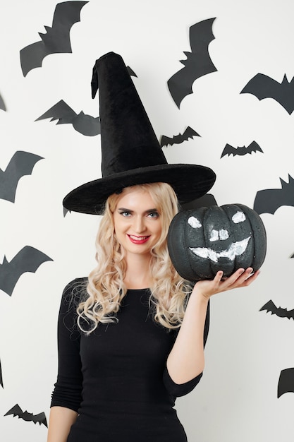 Woman in Halloween costume showing black pumpkin