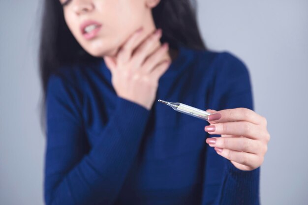 Woman hand in ache throat and thermometer