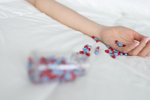 Woman hand after overdose of medical pills on bed