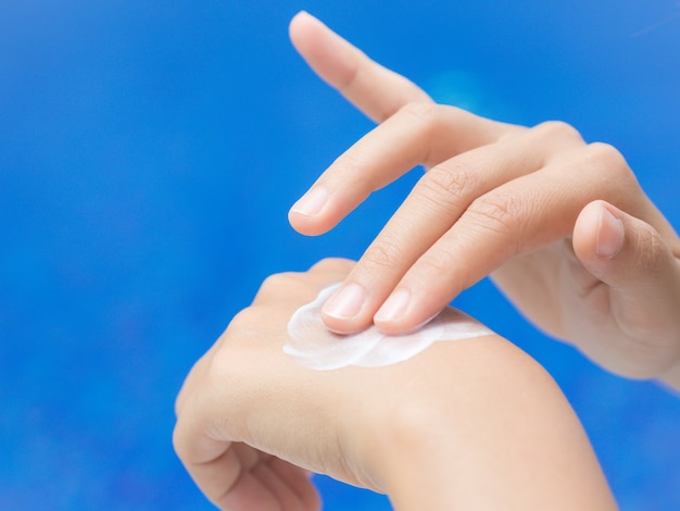 Woman hand apply sunscreen / sunblock by the swimming pool.