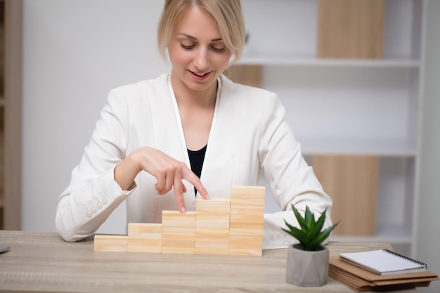 Woman hand arranging wood block stacking as step stair