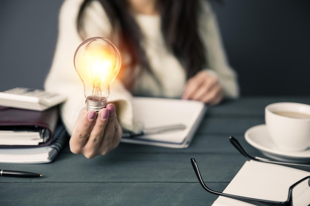 Woman hand bulb on office desk