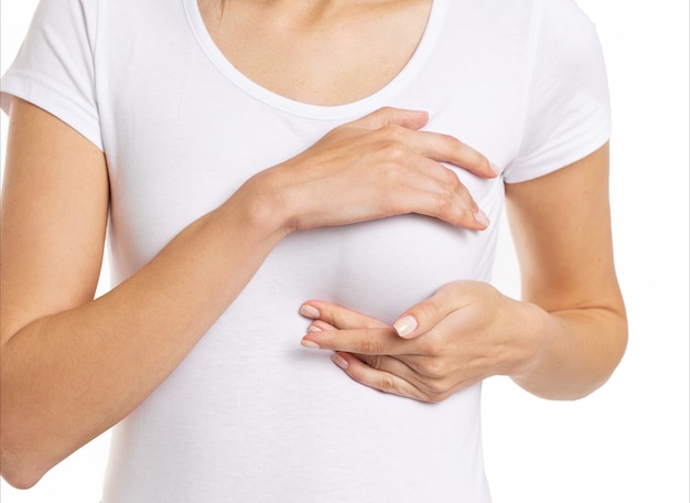 Woman hand checking lumps on her breast for signs of breast cancer on gray background. Healthcare concept. High quality photo