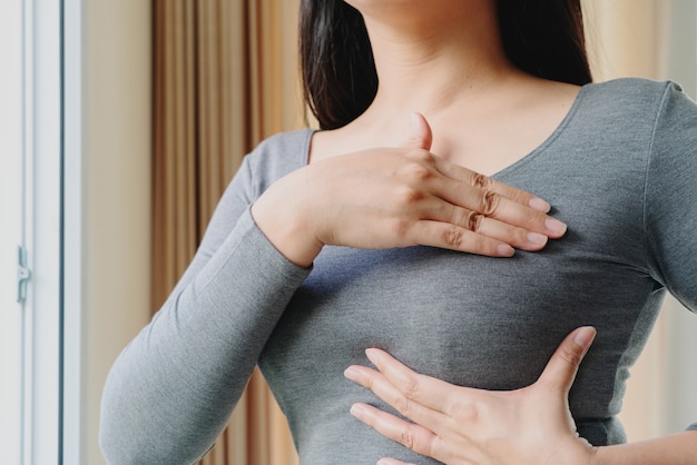 Woman hand checking lumps on her breast for signs of breast cancer