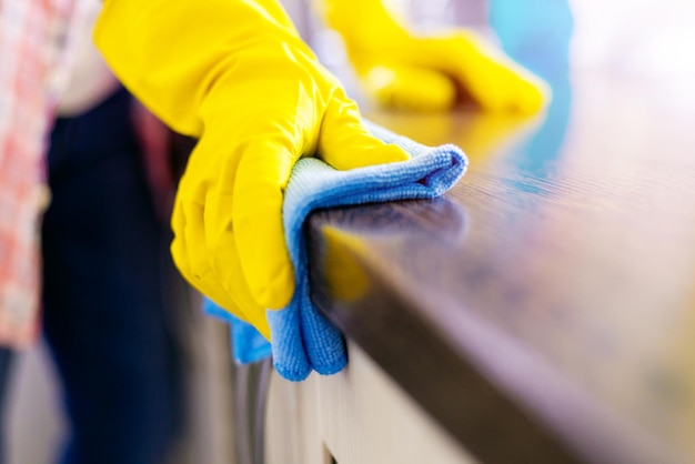 Woman hand cleaning the counter in the kitchen with a blue microfiber cloth