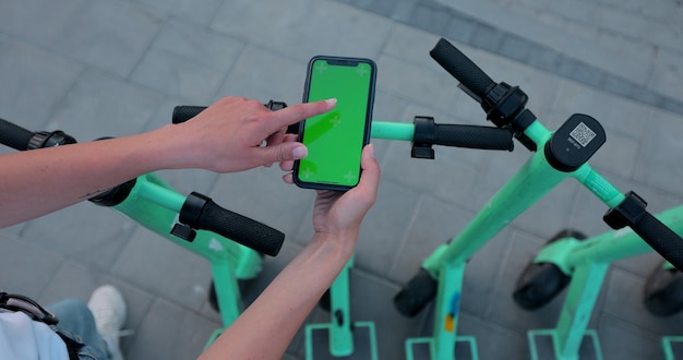 Woman hand click phone with chromakey on background of electric scooter in public park mockup chromakey Urban style riding ecological transport