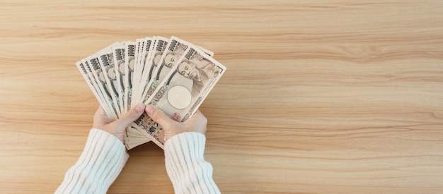 Woman hand counting Japanese Yen banknote over table background Thousand Yen money Japan cash Tax Recession Economy Inflation Investment finance savings salary and payment concepts