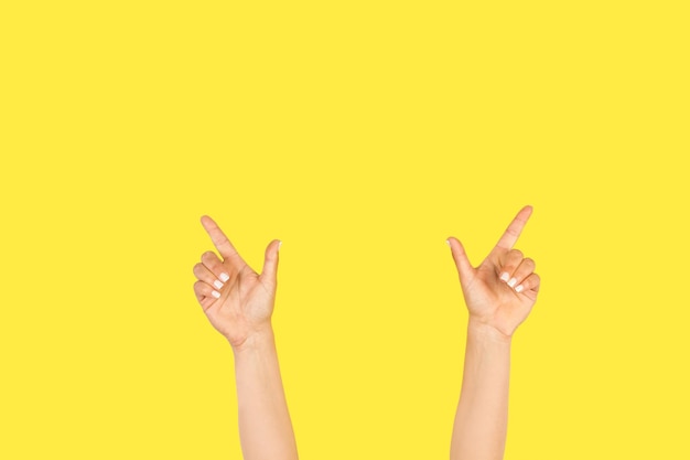 Woman hand doing celebration gesture with both hand on a yellow background