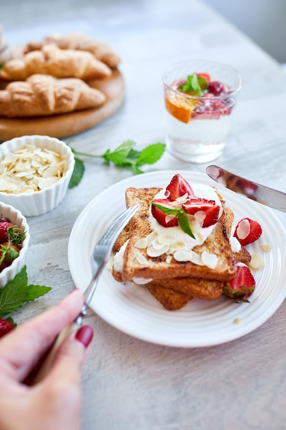 Woman hand eating breakfast of french toast with strawberries