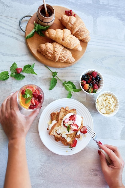 Woman hand eating breakfast of french toast with strawberries