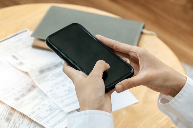 Woman hand entering password code on mobile phone paying bill with credit card bill on desk in home office internet digital marketing mobile banking online payment and digital technology concept