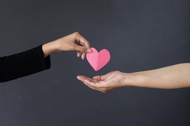 Photo woman hand gives a red heart to a hand for blood donation concept. world blood donor day.