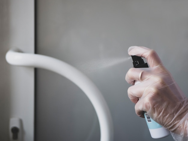 Woman hand in glove is applying sanitizer on the door handle Antiseptic treatment in public places