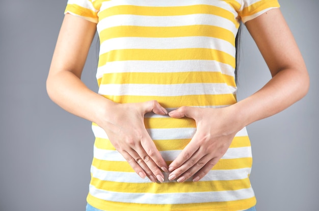 Woman hand heart sign in belly