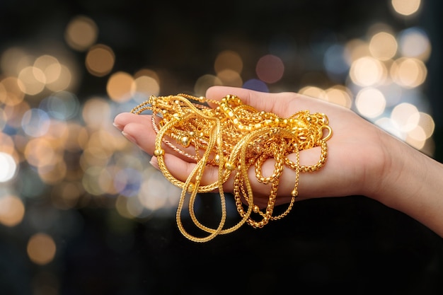 woman hand hold gold bracelet and necklace jewelry