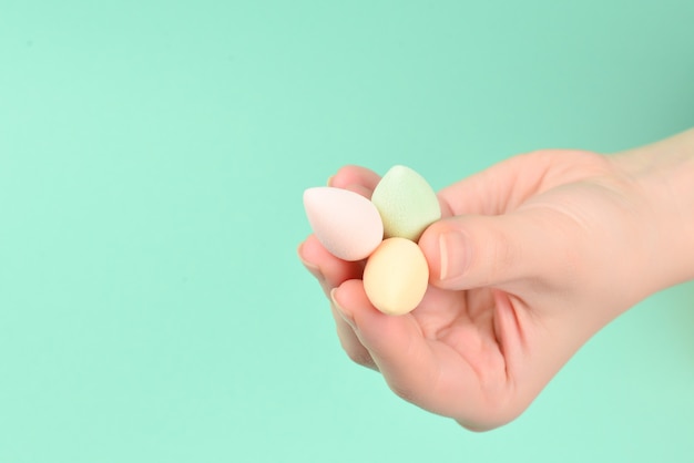 Woman hand holding  beauty sponge  on green background.