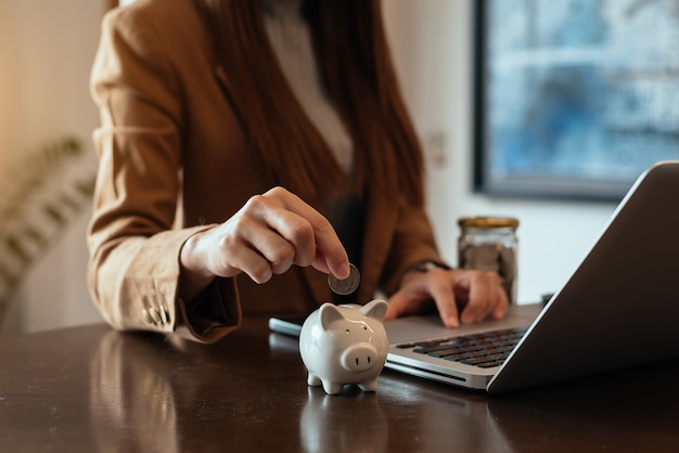 Woman hand holding coin with pig piggy bank. Saving and financial accounts concept