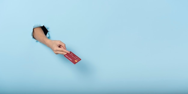 Woman hand holding credit card on blue banner background. Panoramic image