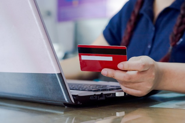 Woman hand holding credit card and using laptop computer