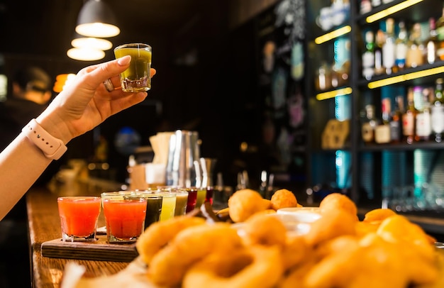 A woman hand holding a glass shot with a green alcoholic drink Alcohol consumption Horizontal photo