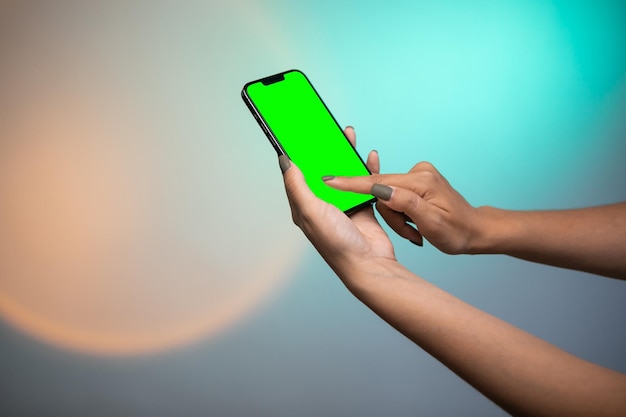 Woman hand Holding a Green Screen Smartphone scroll and touch display on colorful background.