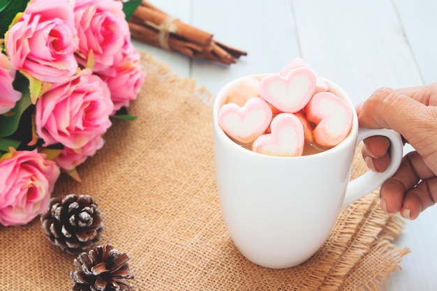 Woman hand holding a hot chocolate with pink marshmallows on top. Love, beauty, Valentine's Day