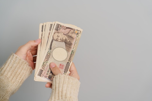 Woman hand holding Japanese Yen banknote stack Thousand Yen money Japan cash Tax Recession Economy Inflation Investment finance and shopping payment concepts