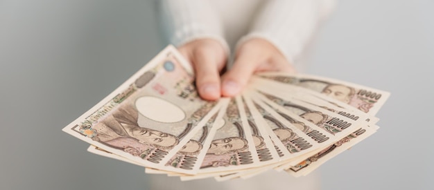 Woman hand holding Japanese Yen banknote stack Thousand Yen money Japan cash Tax Recession Economy Inflation Investment finance and shopping payment concepts