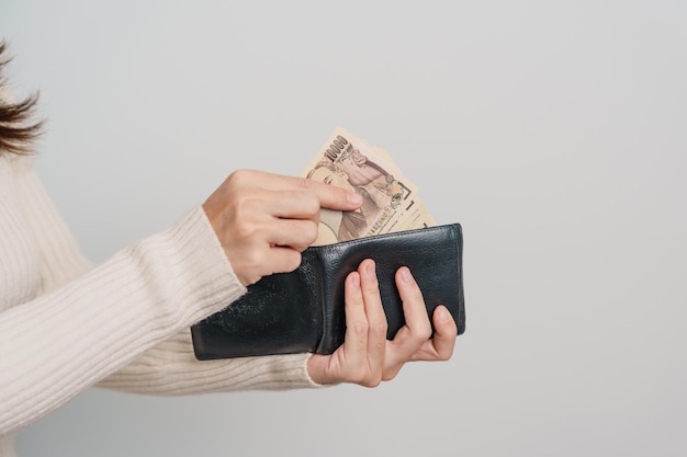 Woman hand holding Japanese Yen banknote with wallet Thousand Yen money Japan cash Tax Recession Economy Inflation Investment finance and shopping payment concepts