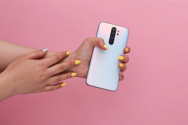 Woman hand holding modern smarphone on pink pastel