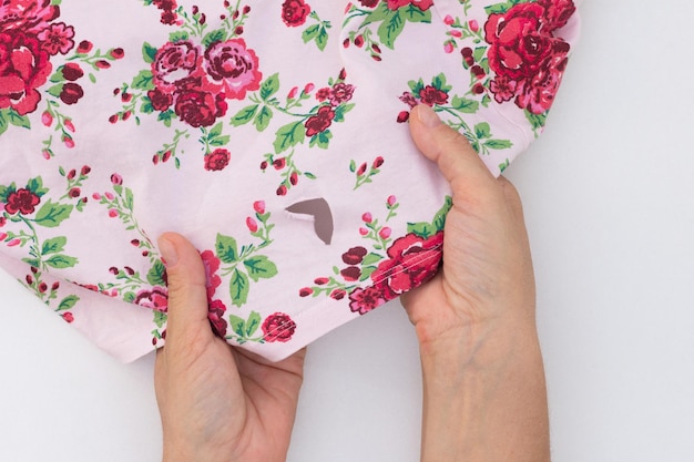 Woman hand holding torn cloth showing hole on the white background