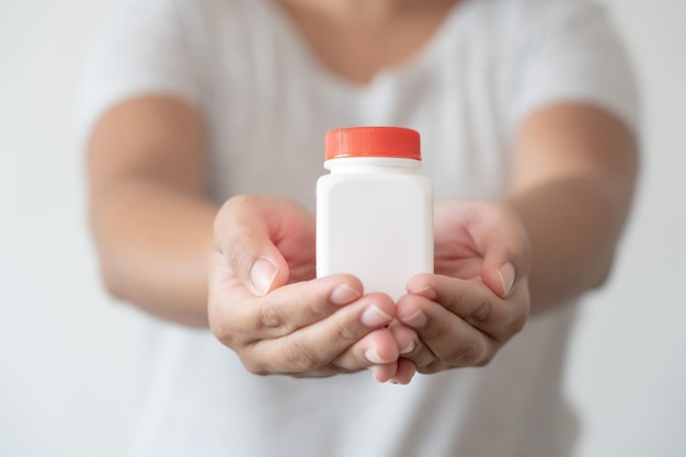 Woman hand holding white bottle free space for text healthcare and medical concept