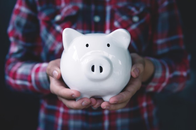 Woman hand holding white piggy bank to saving money conceptbudget financial