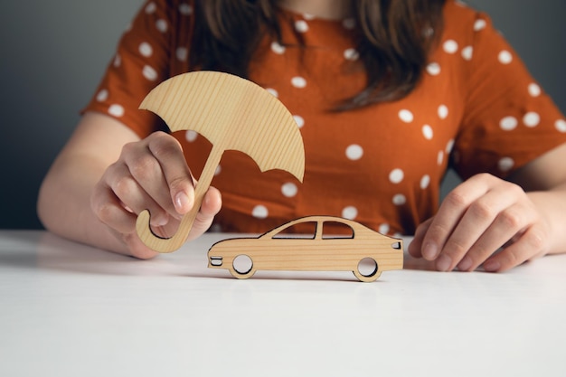 Woman hand holding wooden umbrella over car