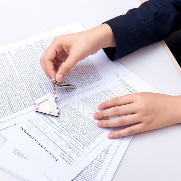 Woman hand and home key. Signed contract and keys of the property with documents. 