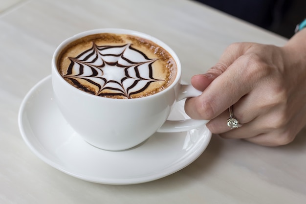 Woman hand is holding a cup of hot coffee.