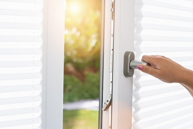 woman hand openes a white plastic pvc window with roller