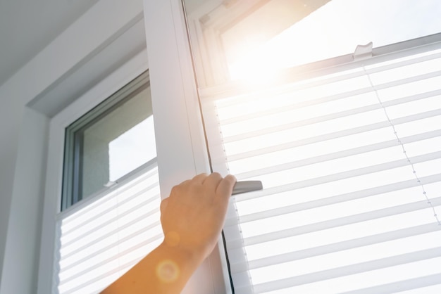 woman hand opens a pvc window with roller