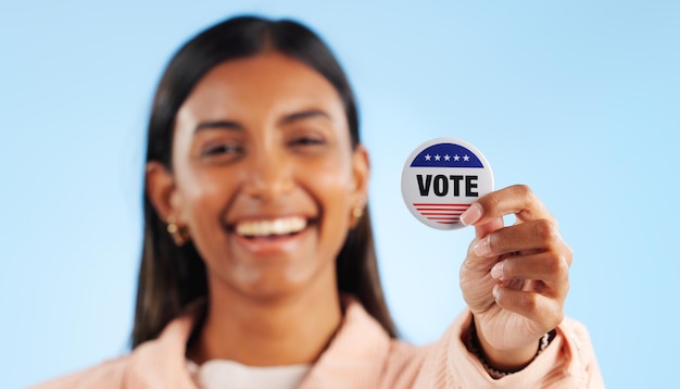 Woman hand and pin for vote by showing in studio for mock up in politics on blue background Indian person smile and excited for government election or campaign with support in community engagement