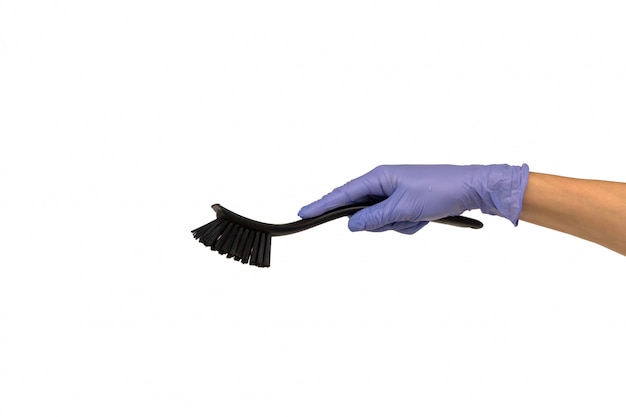 Woman hand in a purple rubber glove holds black dishwashing brush with a plastic handle