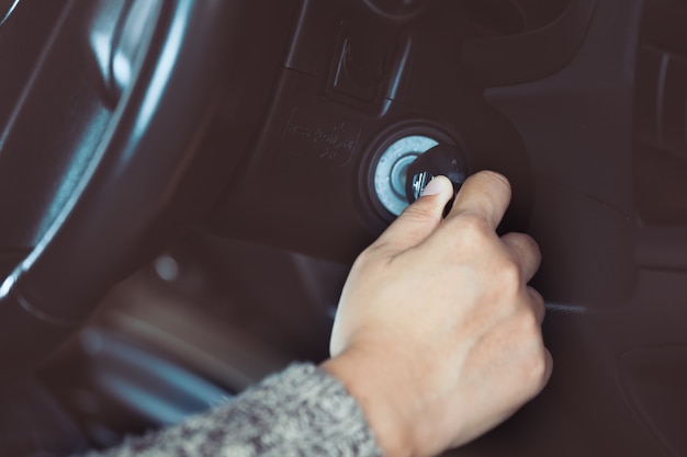 Photo woman hand put key into the ignition and starts the car engine in vintage color tone