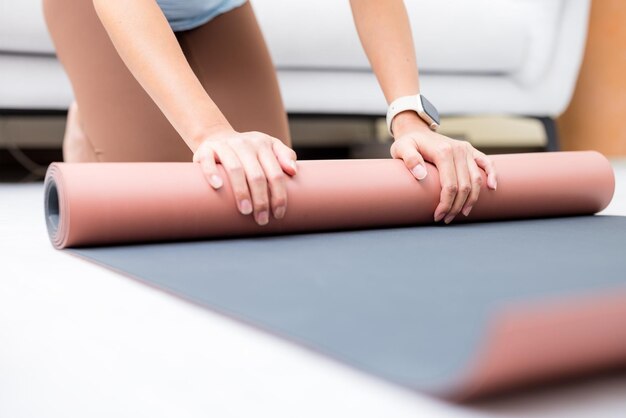 Woman hand roll up yoga mat at home