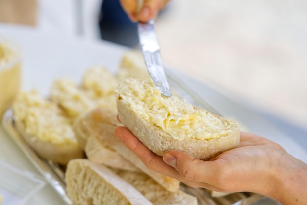 Woman hand spreads bread with cheese salad with garlic the process of preparing a snack for a grill party